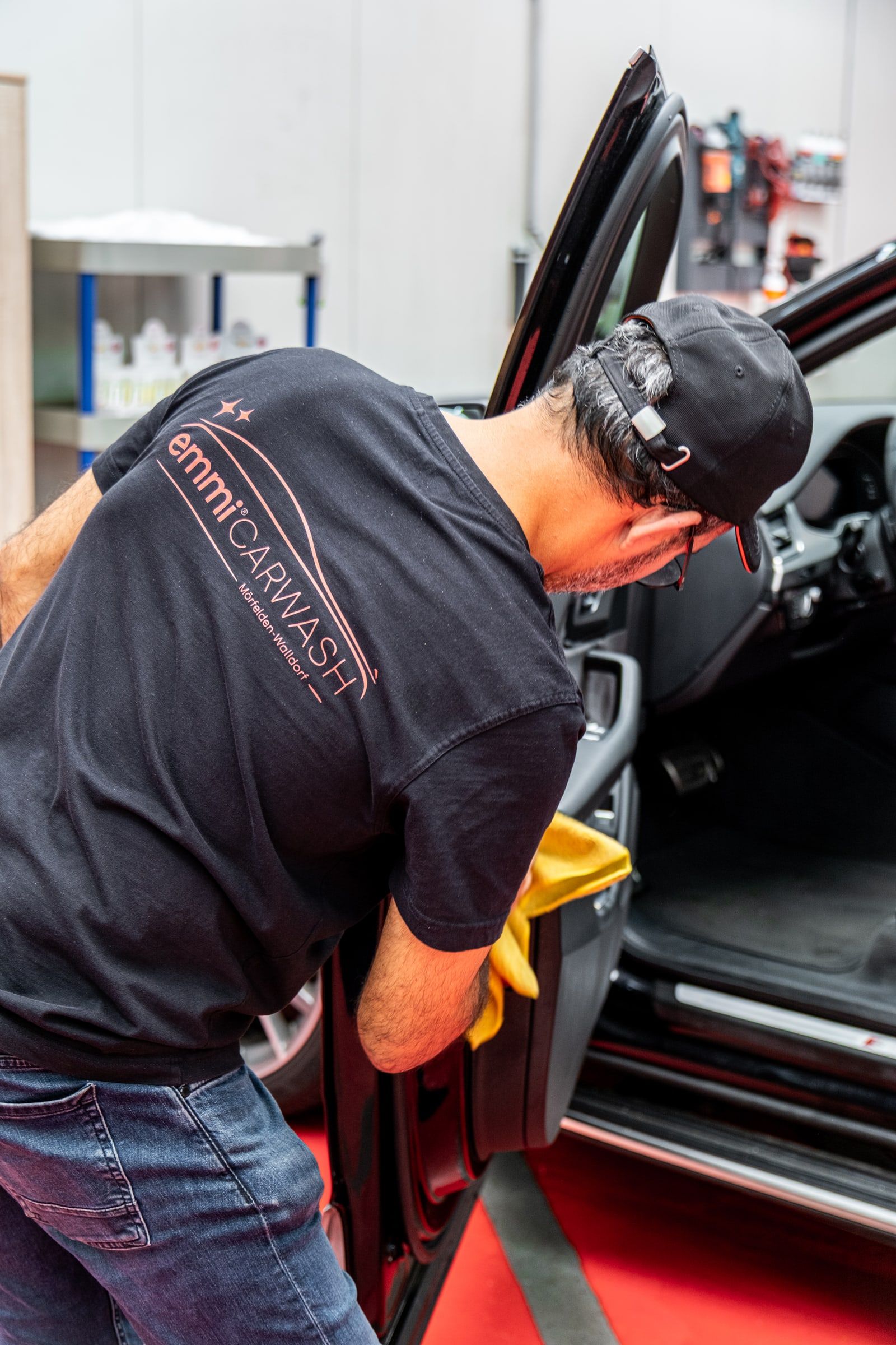 Mitarbeiter von emmi Carwash reinigt den Innenraum eines Autos von Hand