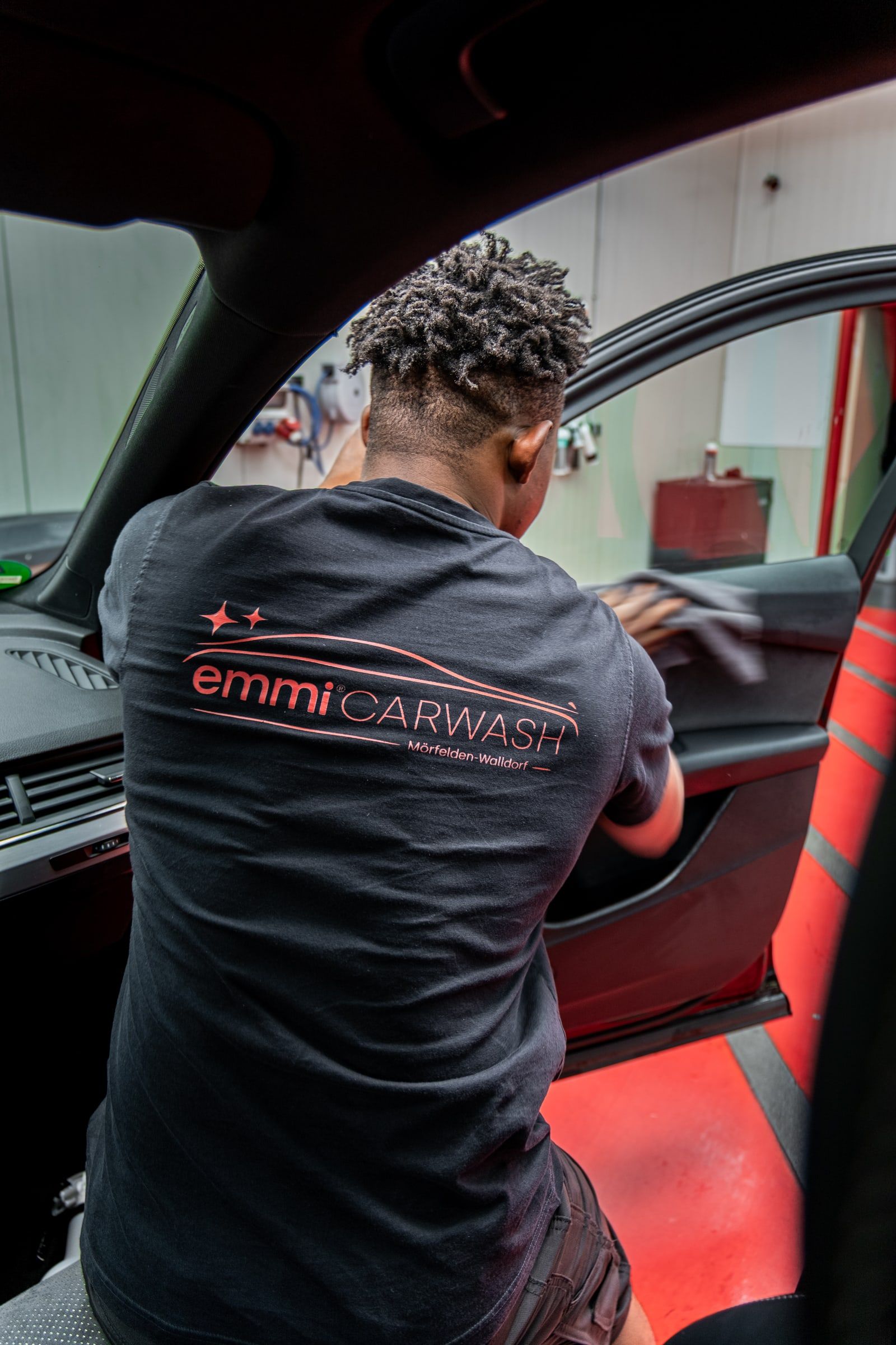 Mitarbeiter von emmi Carwash arbeitet im Innenraum eines Autos