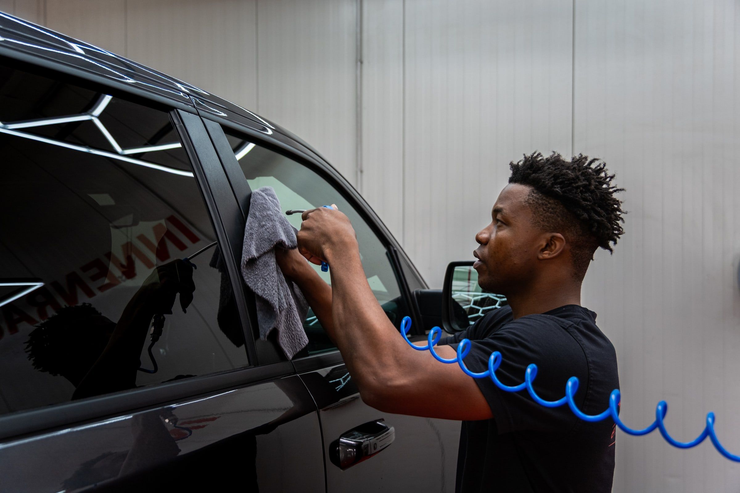 Mitarbeiter von emmi Carwash reinigt die Scheibe eines Autos von Hand