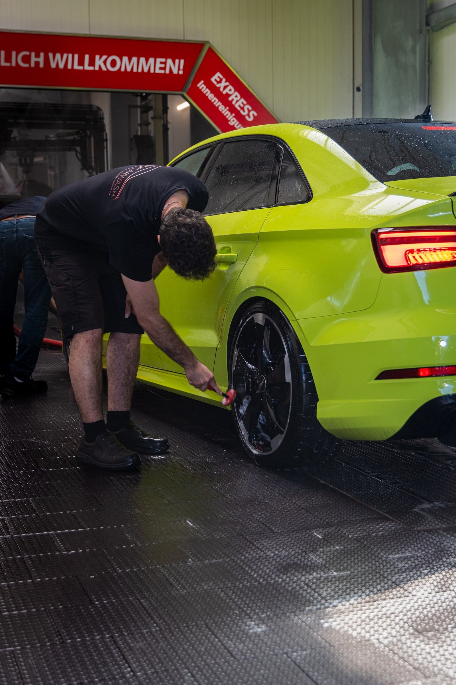Mitarbeiter von emmi Carwash reinigt eine Felge von Hand