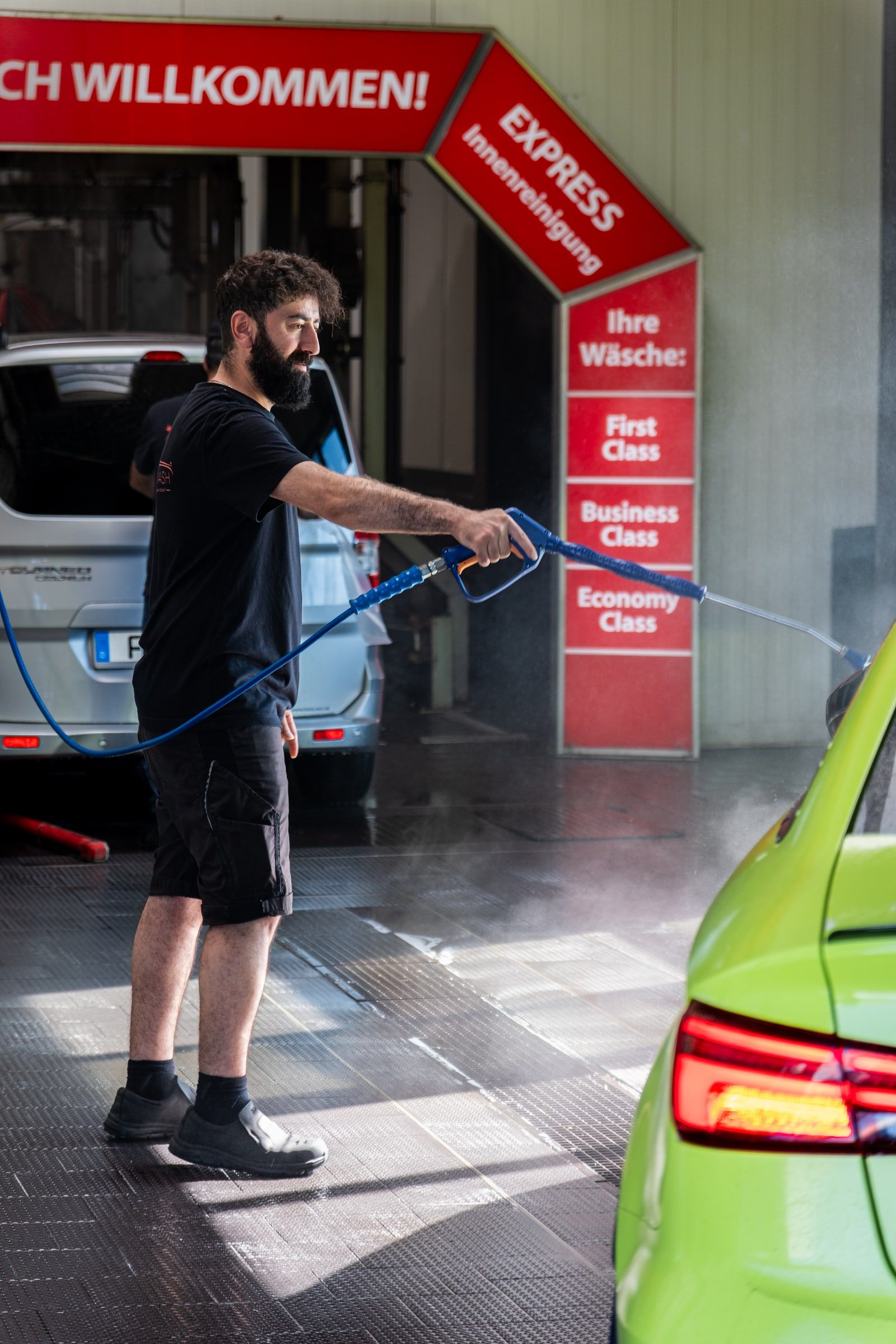 Mitarbeiter von emmi Carwash bei der Hand-Vorwäsche mit dem Hochdruckreiniger